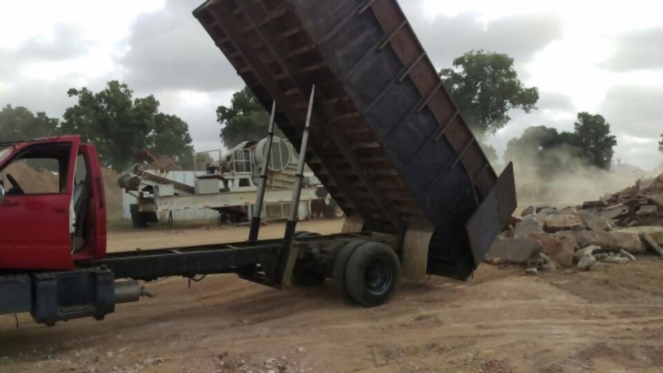 Red dump truck unloading a load of debris