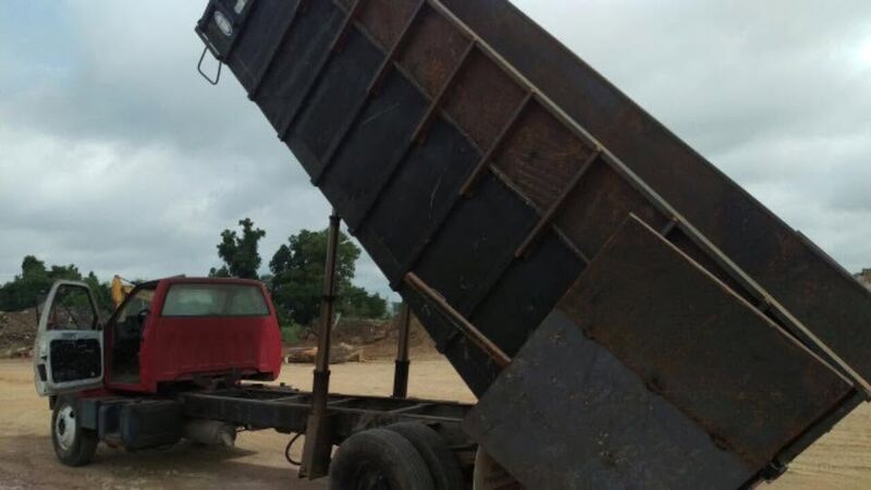 Dump truck with its bed raised, unloading debris